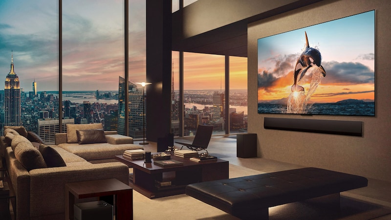 寬敞的客廳，窗外可見城市景觀。LG OLED TV 安裝在牆上，並搭配一部 LG Soundbar。電視的一體牆面設計使其可無縫貼合牆面，與空間完美融合。Zero Connect Box 雖可看見，但十分隱蔽。